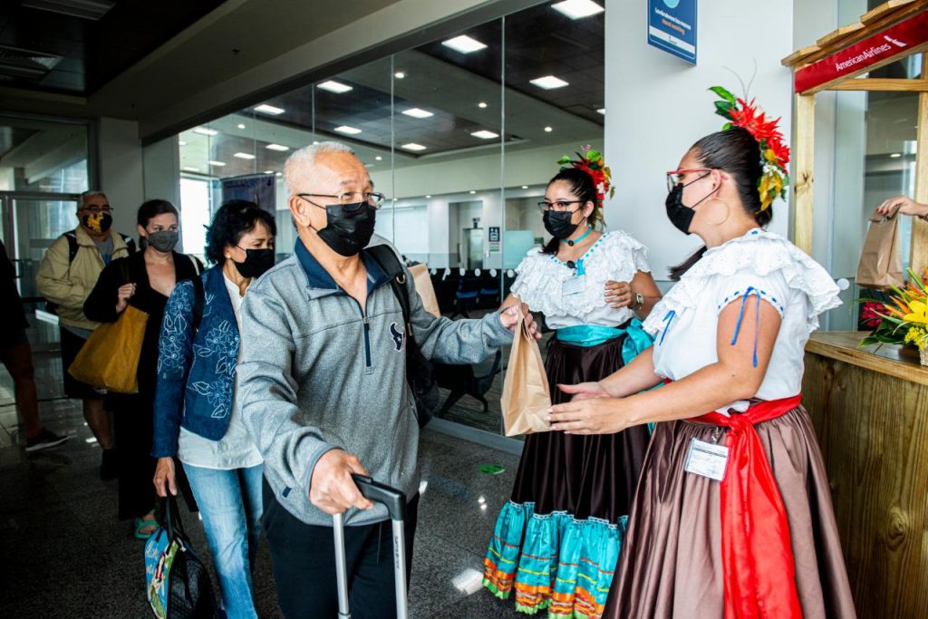 personas que arriban a Costa Rica y son recibidas por mujeres con trajes típicos 